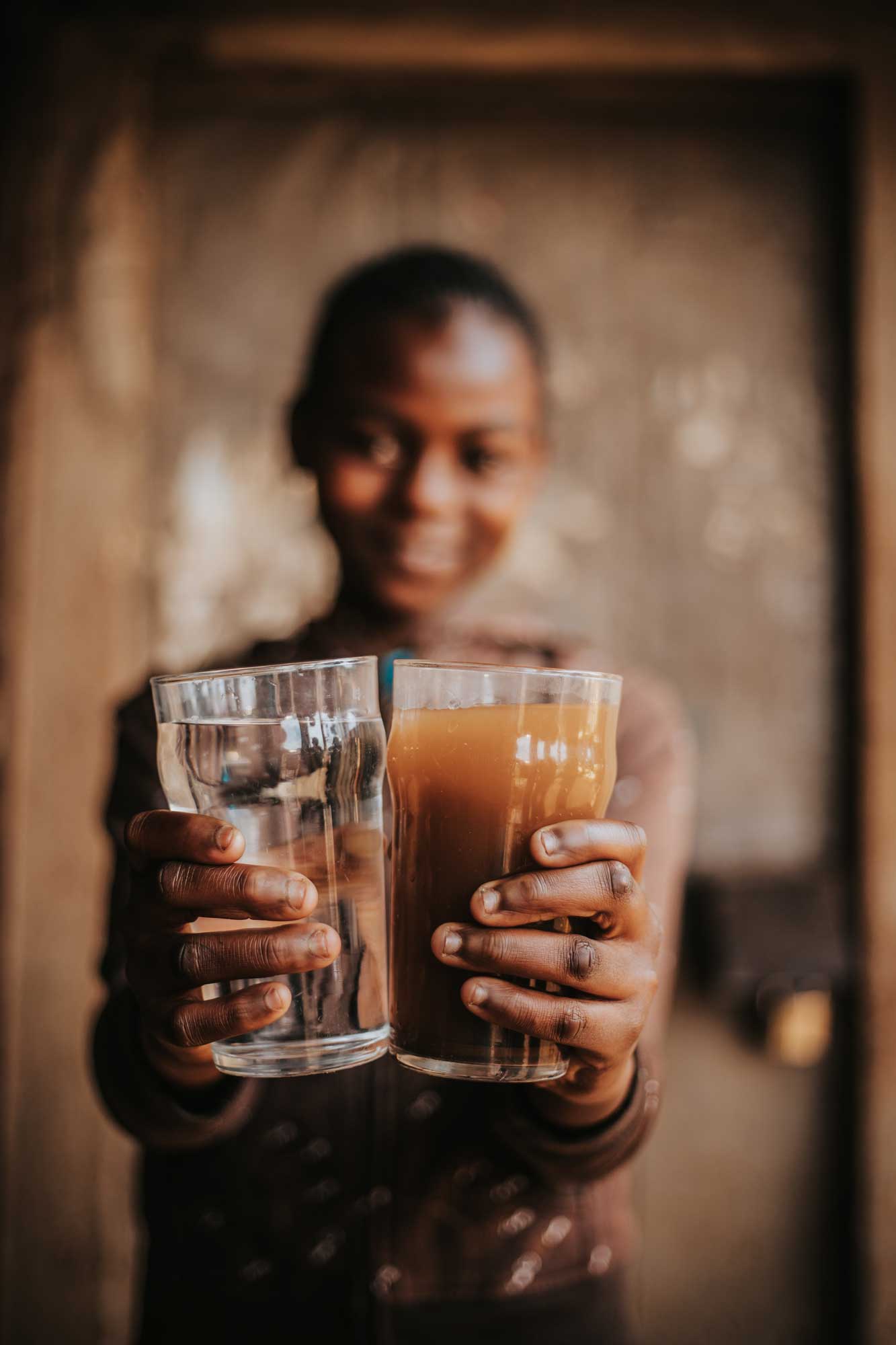 A Kibera Resident Holding a Cup of Filtered Water Next to a Cup of Unfiltered Water